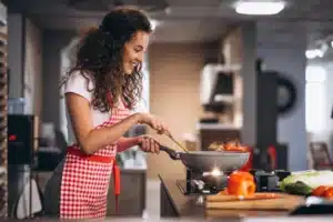 femme souriante en tablier a carreaux cuisinant dans une poe