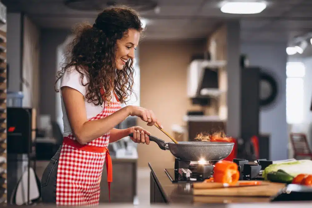 femme souriante en tablier a carreaux cuisinant dans une poe