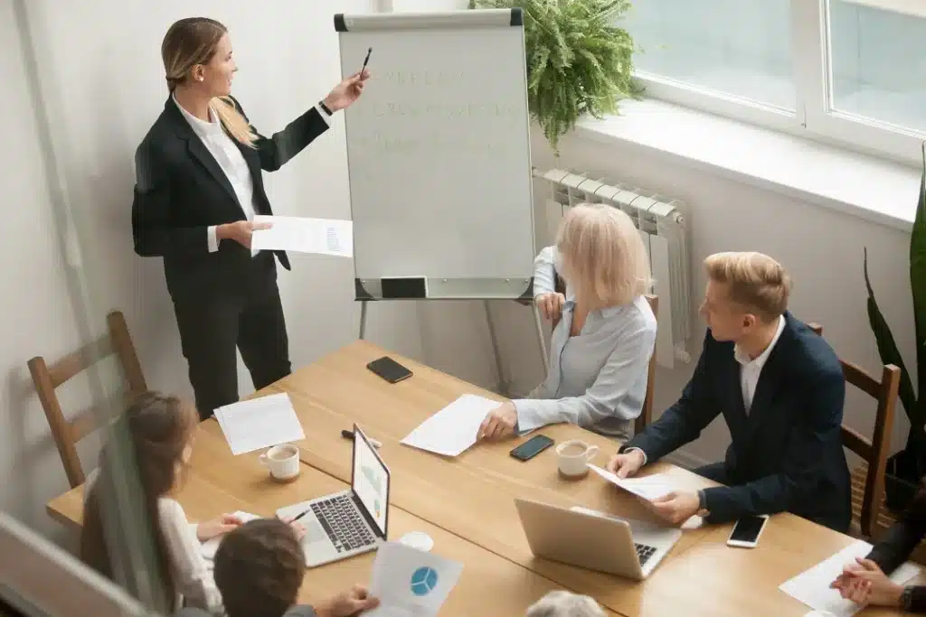 presentation par une femme en costume devant un tableau blan