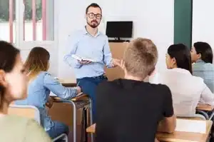 professeur expliquant un livre a des etudiants dans une sall