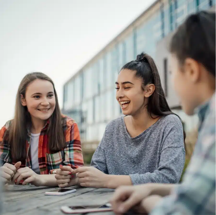 trois jeunes filles souriantes a une table en bois devant un