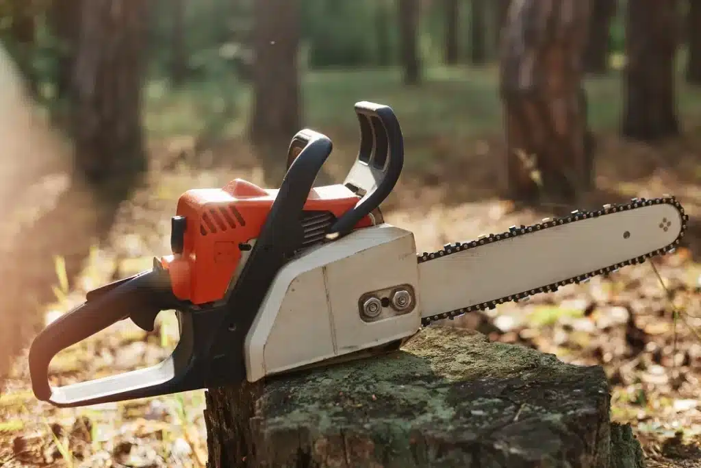 tronconneuse orange et blanche posee sur une souche en foret