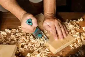 mains travaillant le bois avec un rabot copeaux sur un etabl (1)